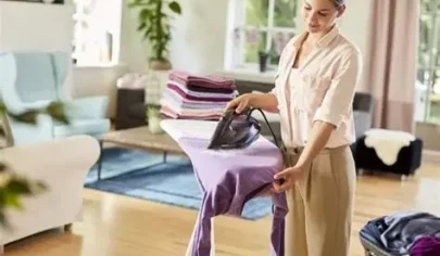 اتوی سنتی روی میز اتو، با بخار در حال کار